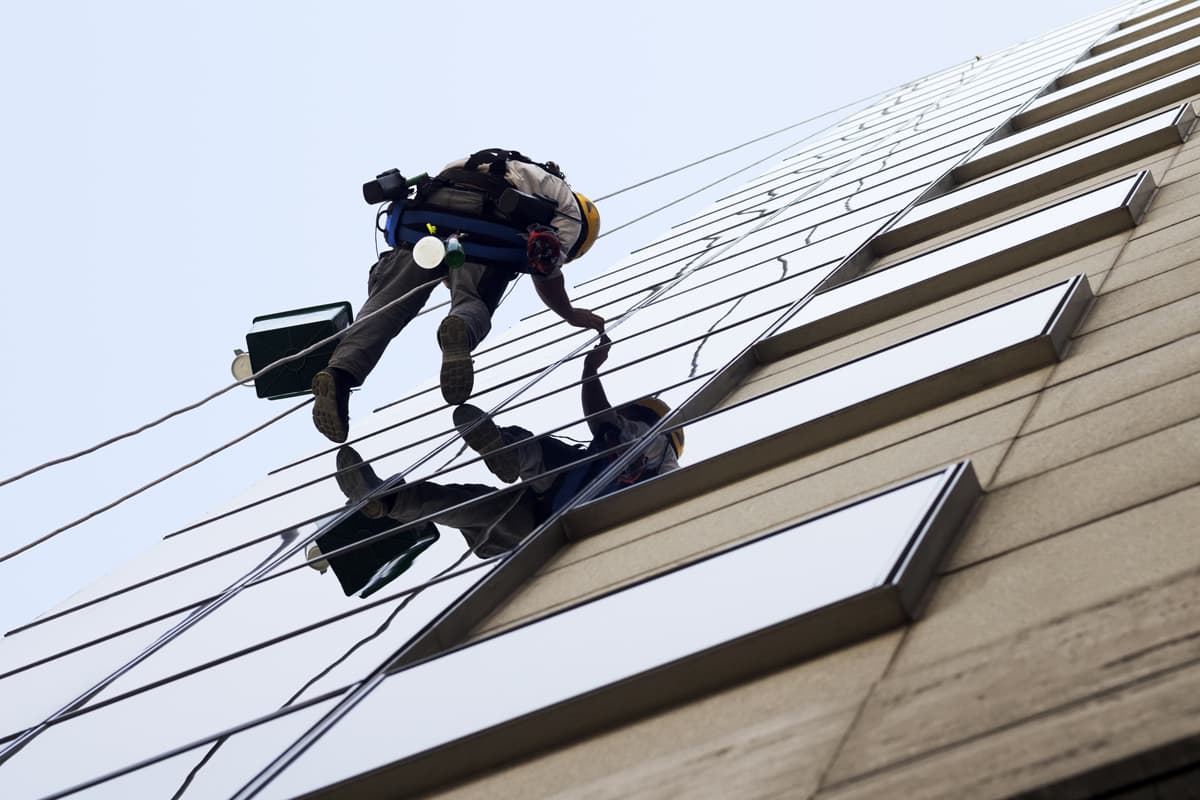 Operario realizando trabajos verticales en Santander y Cantabria pintando una junta de fachada suspendido con cuerdas
